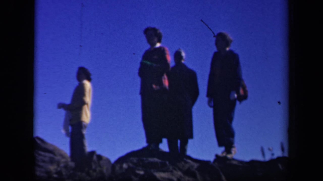 Four women stand silhouetted on rocks against a deep blue sky.