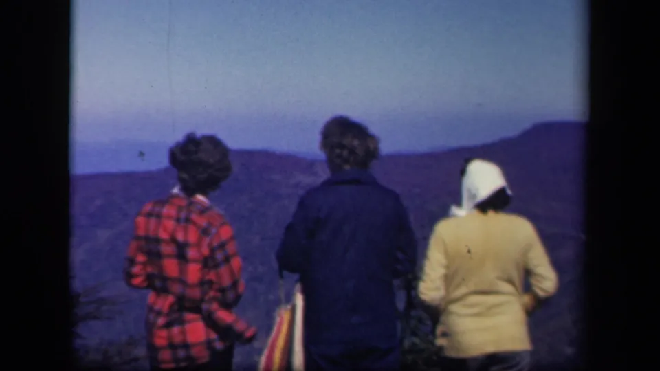 Three women viewed from behind at Skyline Drive in 1943, facing layered mountain ridges in soft 8mm color.