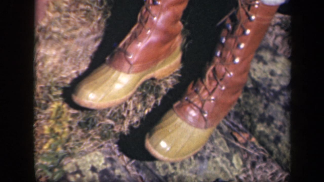Close-up from 1943 Skyline Drive footage showing brown lace-up boots with yellow rubber toe caps on an outdoor ground surface.