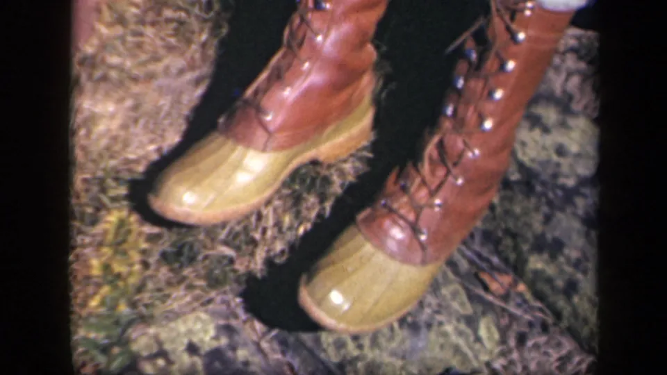 Close-up from 1943 Skyline Drive footage showing brown lace-up boots with yellow rubber toe caps on an outdoor ground surface.