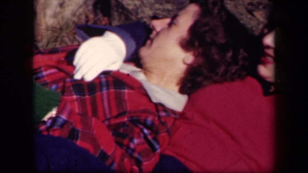 In a close outdoor 8mm frame, two adult women recline at Skyline Drive, Virginia, with a white glove and plaid fabric visible.