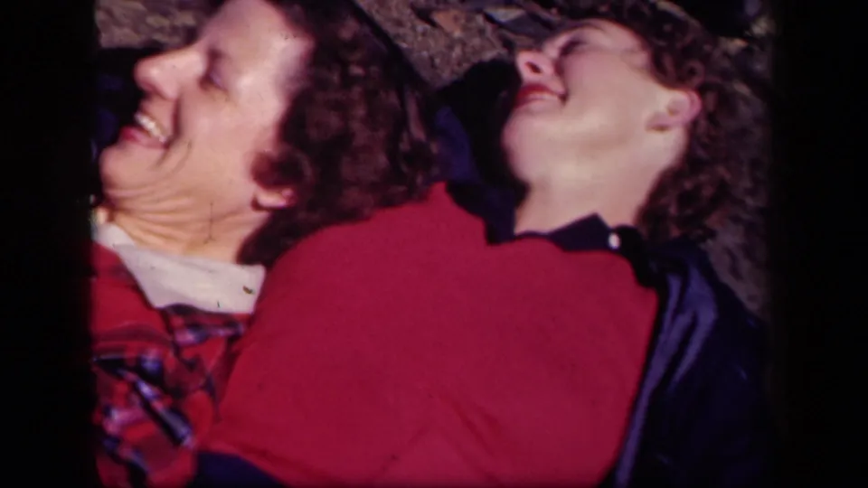 The two women continue laughing on the ground at Skyline Drive, Virginia, in a close 1943 8mm home-movie frame.