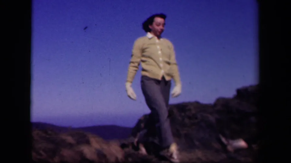 In the final frame, the woman moves forward on the Skyline Drive rocks, with her face, gloves, cardigan, and trousers visible.