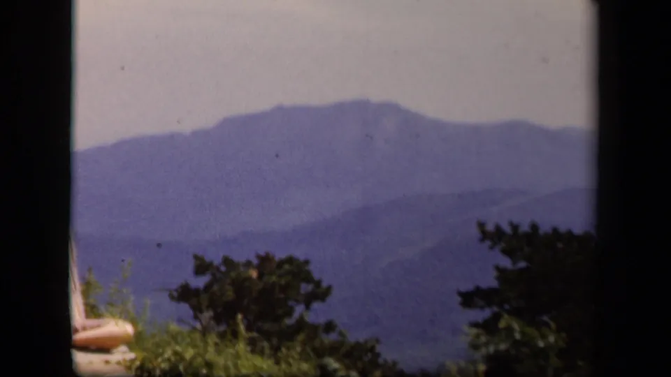 A 1943 Skyline Drive view shows hazy blue mountain ridges, foreground greenery, and the soft color of 8mm home-movie film.