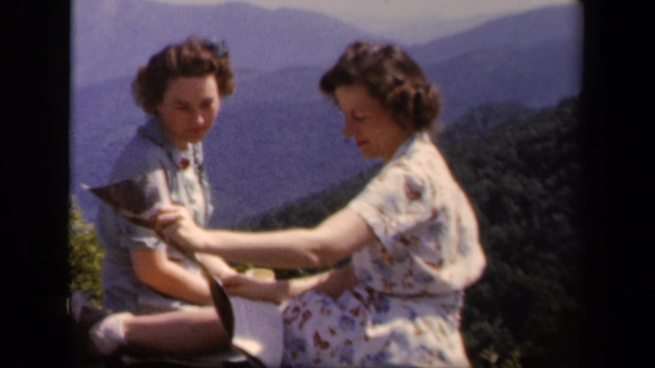 At a Skyline Drive mountain overlook, two women in period clothing handle a folded map with layered ridges in the background.