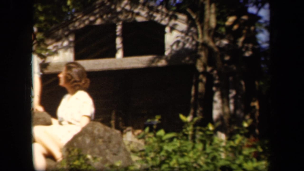 Two young women remain near rocks and trees, with one seated and one standing partly out of frame.