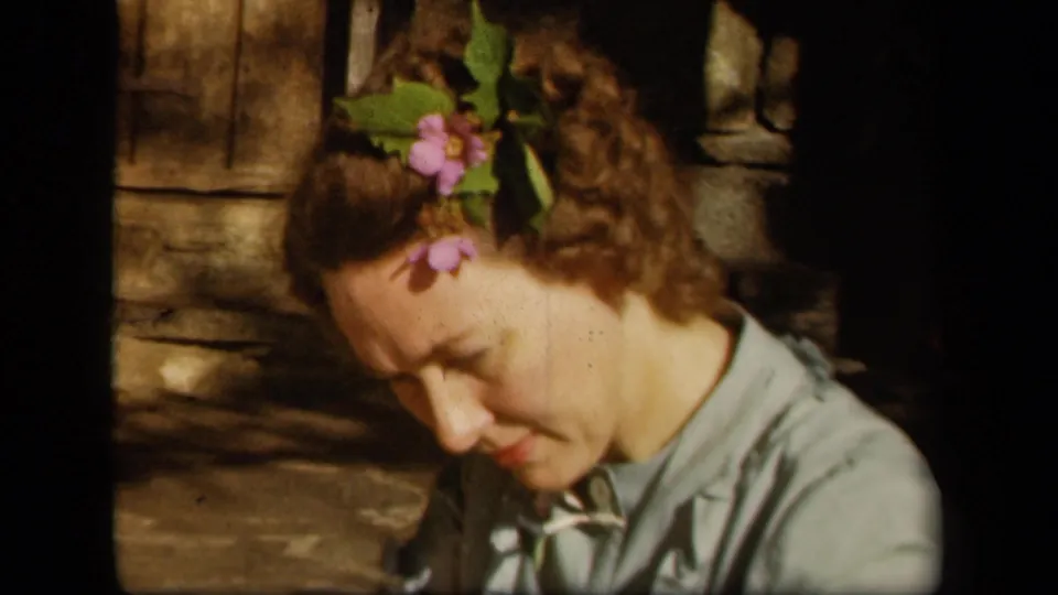 Close home-movie view of an adult woman with flowers in her hair looking downward at Skyline Drive in 1943.