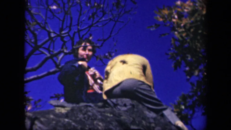 At Skyline Drive in 1943, two women appear on rocks against a vivid blue sky, with branches framing the scene.