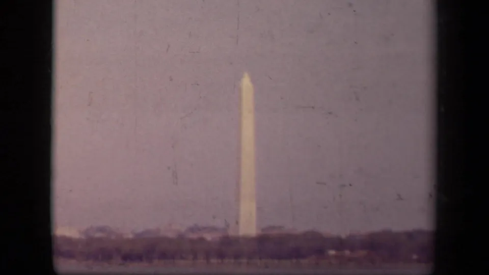 Distant 1943 Washington Monument view from a visitor vantage point, with haze, trees, and 8mm frame edges.