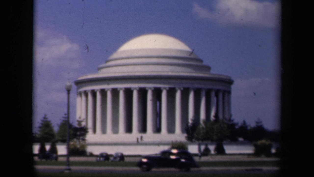 1943 8mm view of the Jefferson Memorial in Washington, D.C., with automobiles crossing the foreground road.