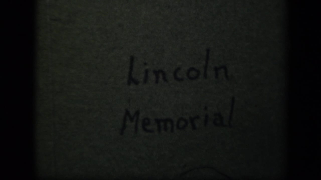 1943 8mm home-movie title card for the Lincoln Memorial, with handwritten text on aged green paper and visible film borders.