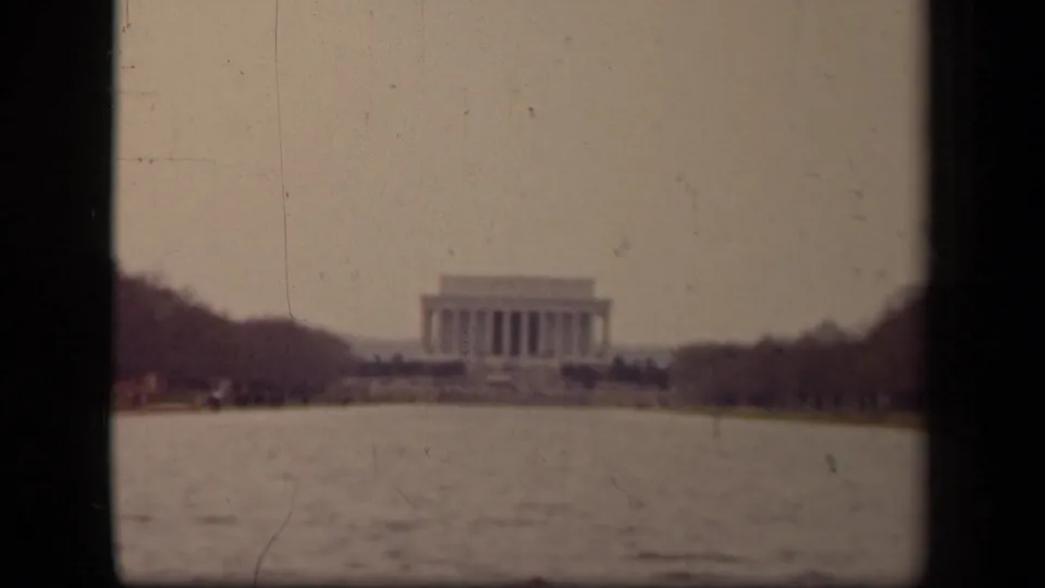 Washington, DC view of the Lincoln Memorial across the Reflecting Pool, with bare trees, hazy sky, faded color, and 8mm film grain.