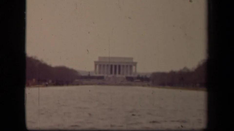 Aged 8mm frame of the Lincoln Memorial from across the Reflecting Pool, with soft detail and visible film wear.