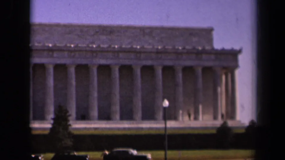 1943 Washington DC home-movie view of the Lincoln Memorial facade with columns, lawn, parked cars, and a lamppost.