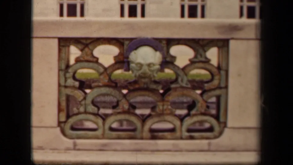 Washington DC architectural detail from 1943, with warm 8mm color and a mask-like sculpted face in the railing.
