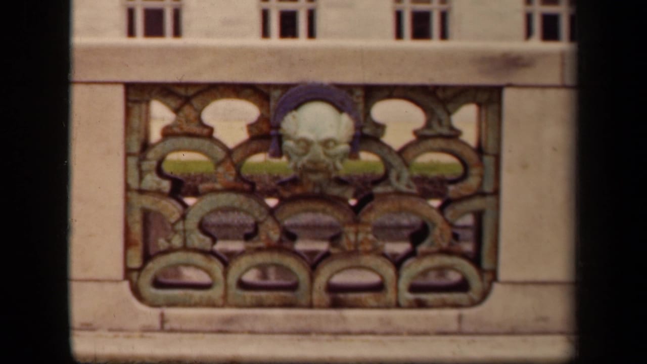 Stone facade detail with a sculpted face above repeating arched ornament.