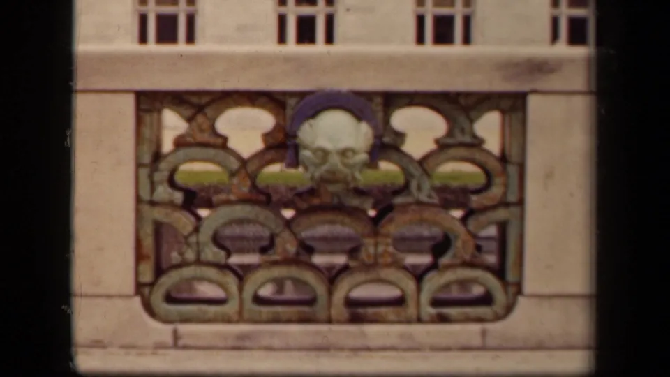 1943 Washington, DC home-movie frame of an ornate stone architectural panel with a face motif and windows above.