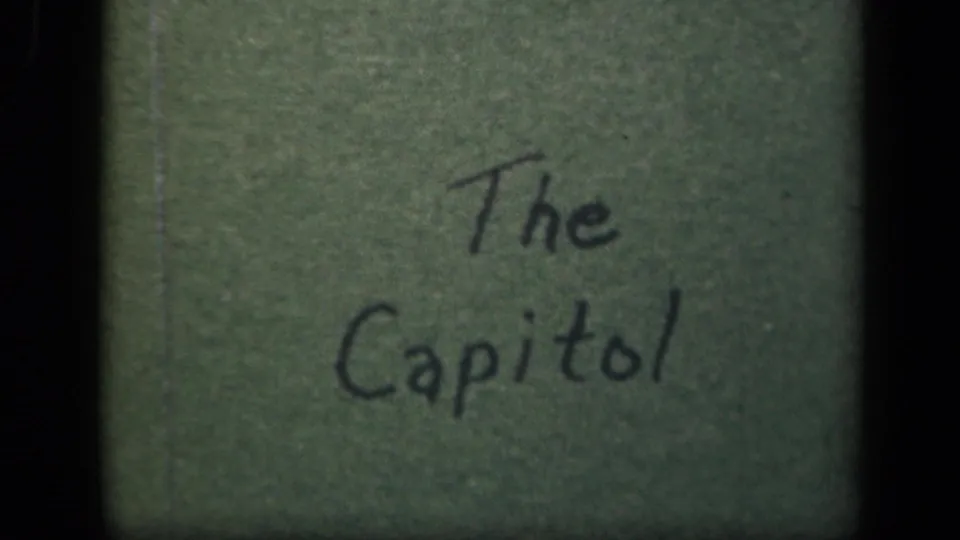 1940s 8mm title card for a Washington, D.C. Capitol view, handwritten on a green background and framed by film edges.