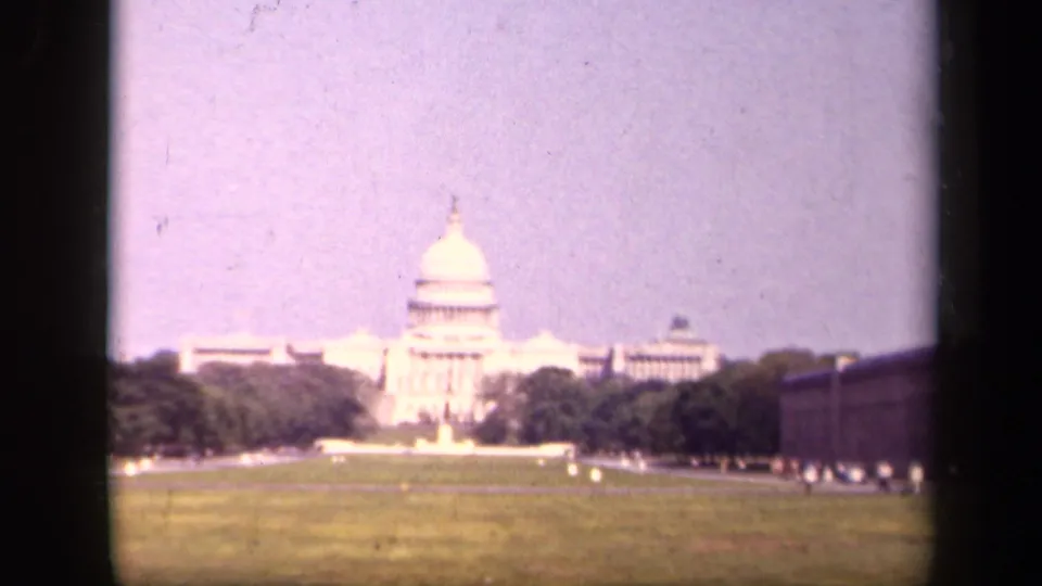 The U.S. Capitol in Washington, D.C., appears in a soft 1940s 8mm view across open lawn and tree-lined grounds.