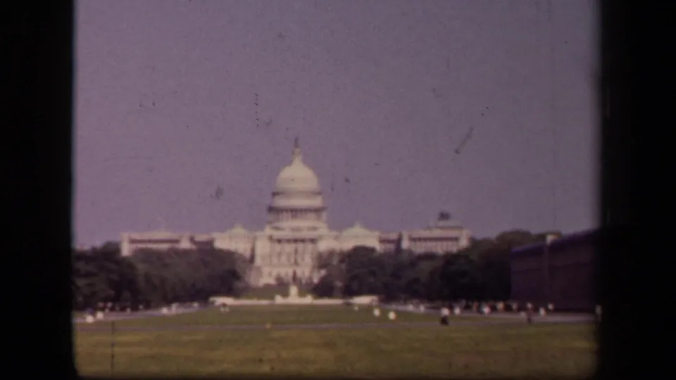 1943 Washington, DC footage shows the U.S. Capitol beyond a broad lawn, with trees, tiny figures, and visible 8mm frame borders.