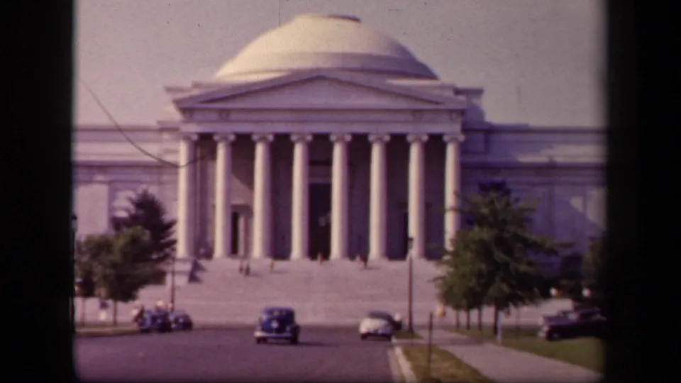 Closer 1943 view of the National Art Gallery entrance, showing columns, steps, roadside trees, automobiles, and tiny pedestrians.
