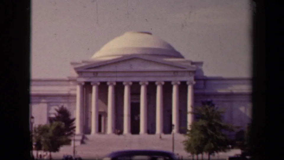 1943 home-movie view of the Jefferson Memorial as a dark automobile passes across the foreground road.