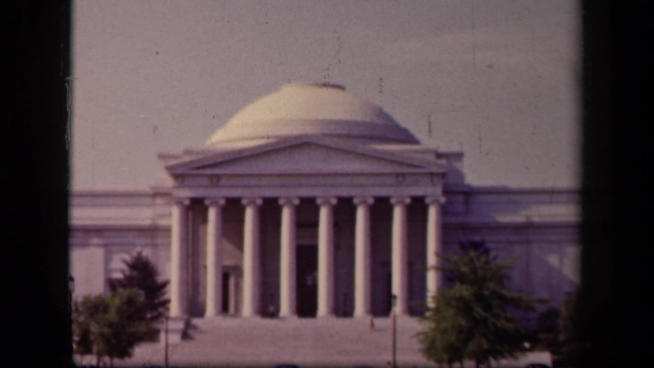 1943 8mm view of the Jefferson Memorial in Washington, DC, framed by dark vertical edges with trees in the foreground.