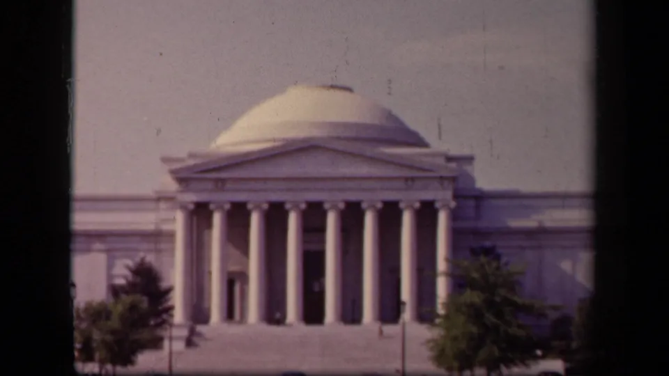 1943 8mm view of the Jefferson Memorial in Washington, DC, framed by dark vertical edges with trees in the foreground.