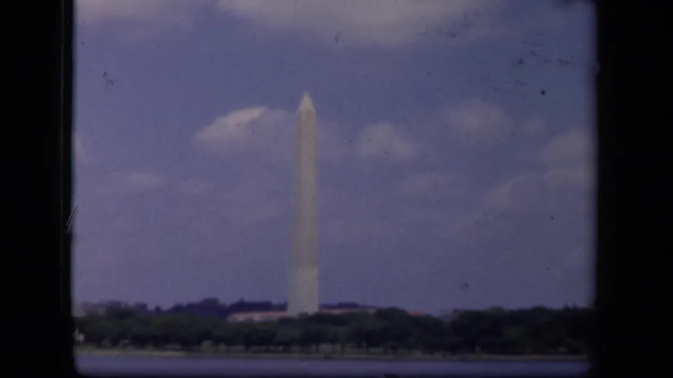 Distant 1943 8mm view of the Washington Monument in Washington, DC, seen across water and a treeline.