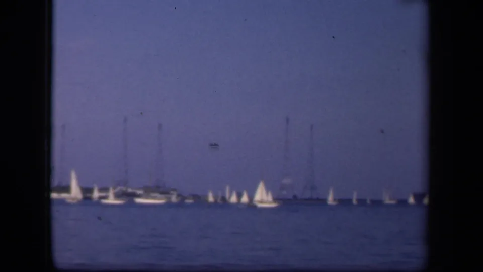 Vintage 8mm waterfront view in Washington, DC, with multiple sailboats and yachts spread across the water.