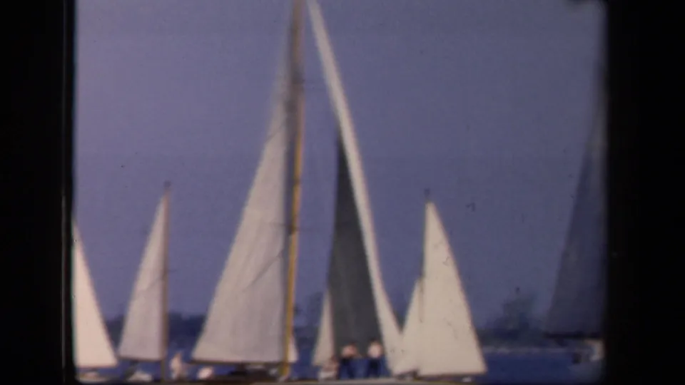 Closer 8mm view of several white-sailed boats on the water, with masts and sails filling much of the frame.