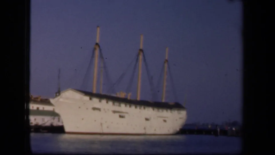 A large white docked vessel appears beside a pier, with masts and calm water visible in the Washington, DC home-movie footage.