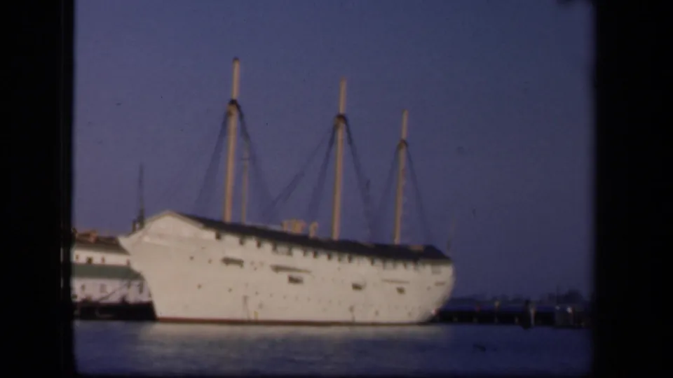 The docked white vessel remains in view, with three masts and rigging silhouetted against the Washington, DC sky.