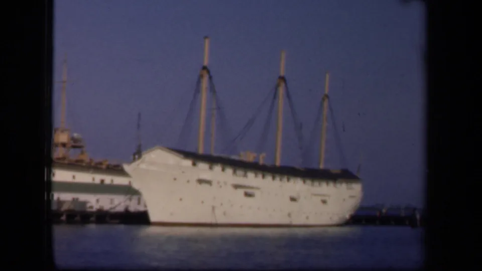 The final frame shows the large docked white ship, its masts, and part of another vessel or dock structure at left.