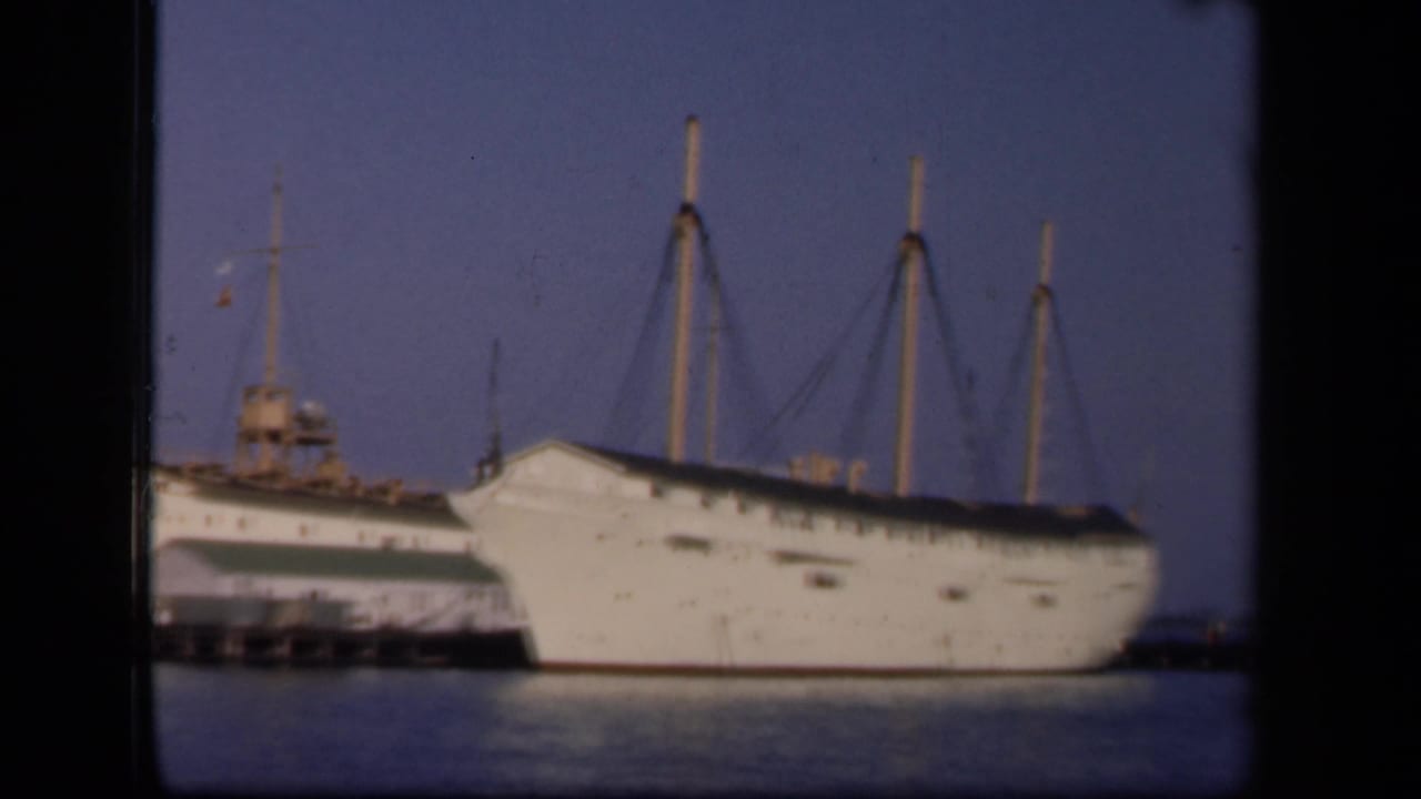 1943 Washington, DC harbor footage showing a large white multi-masted ship docked beside a pier, seen through 8mm film frames.