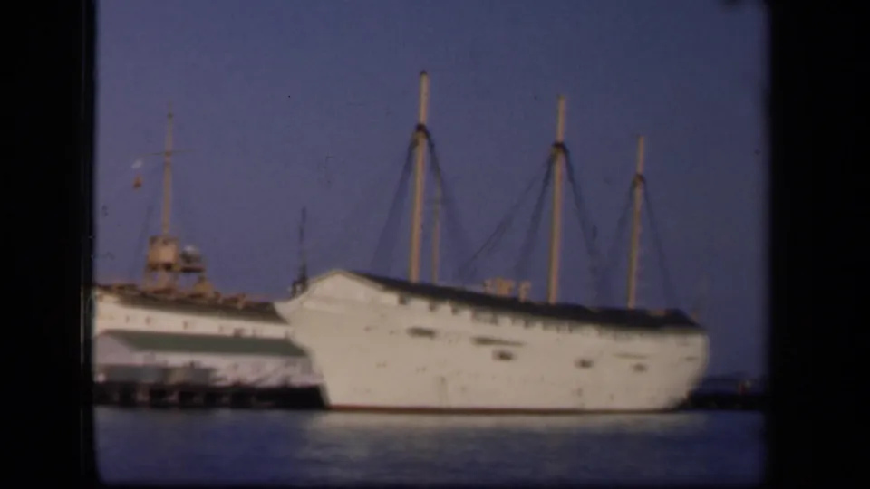 1943 Washington, DC harbor footage showing a large white multi-masted ship docked beside a pier, seen through 8mm film frames.