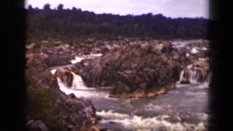 Final 8mm frame of the short 1943 Washington, DC nature clip, with rushing water around rugged rocks and trees behind.