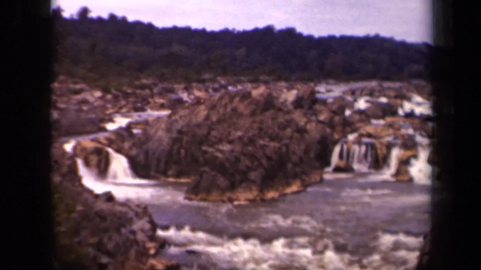 Archival 8mm frame of a rocky waterfall landscape near Washington, District of Columbia, with water dropping on both sides of a rock island.