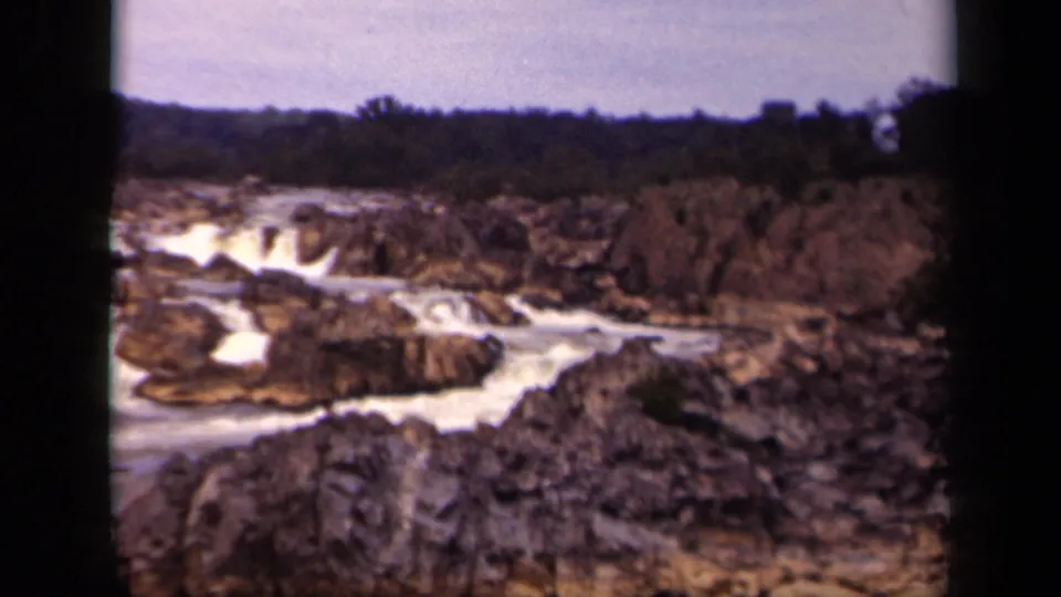 A 1943 Washington, DC 8mm view of river rapids crossing rugged rock ledges below a low tree line.