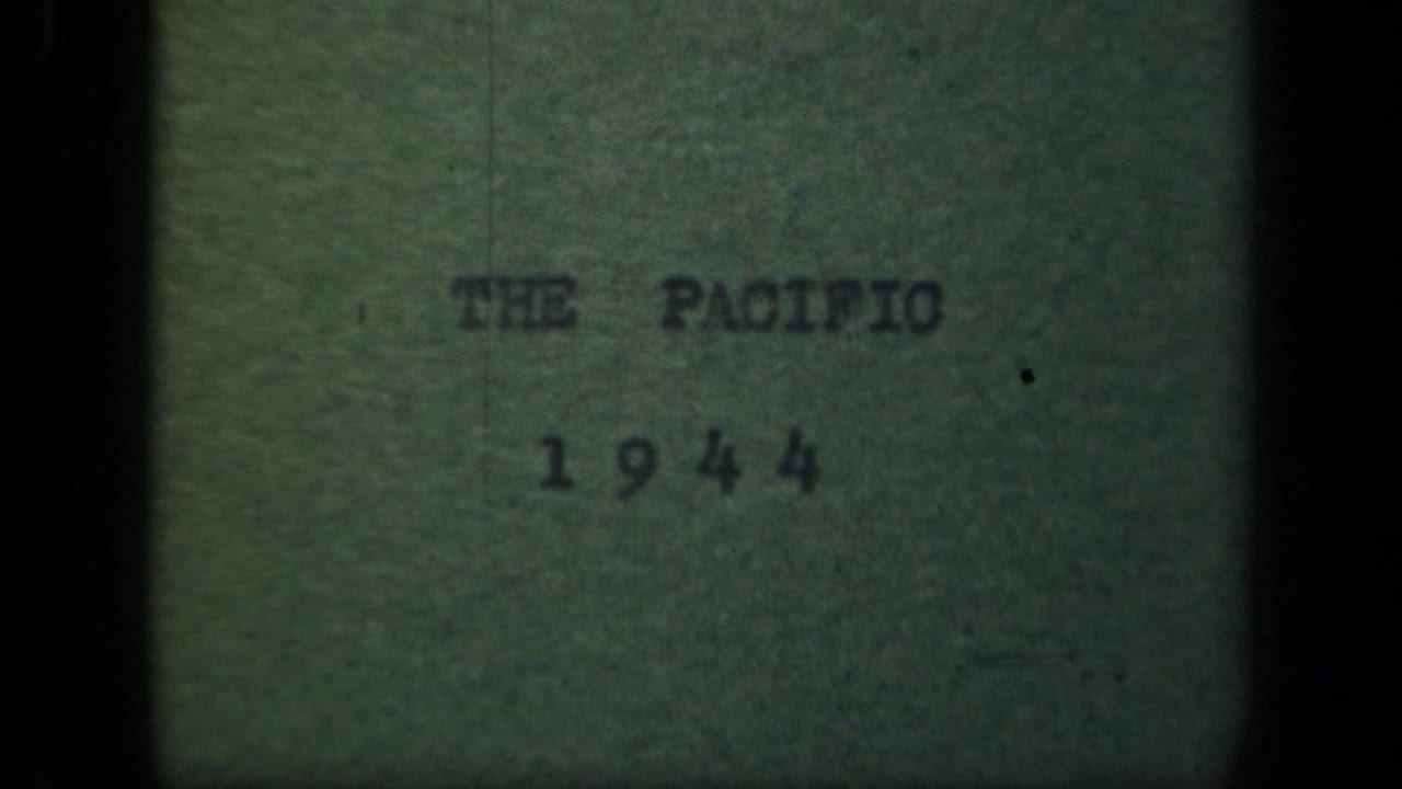 1944 Pacific title card on green paper, with typed text, soft focus, grain, and black 8mm frame edges.