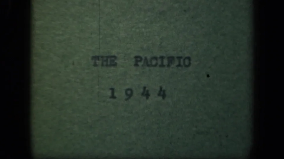 1944 Pacific title card on green paper, with typed text, soft focus, grain, and black 8mm frame edges.