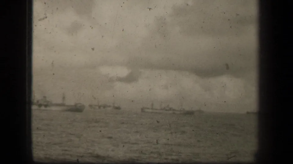 Monochrome 8mm view of several distant naval vessels moving across open water in the Leyte Gulf sequence.