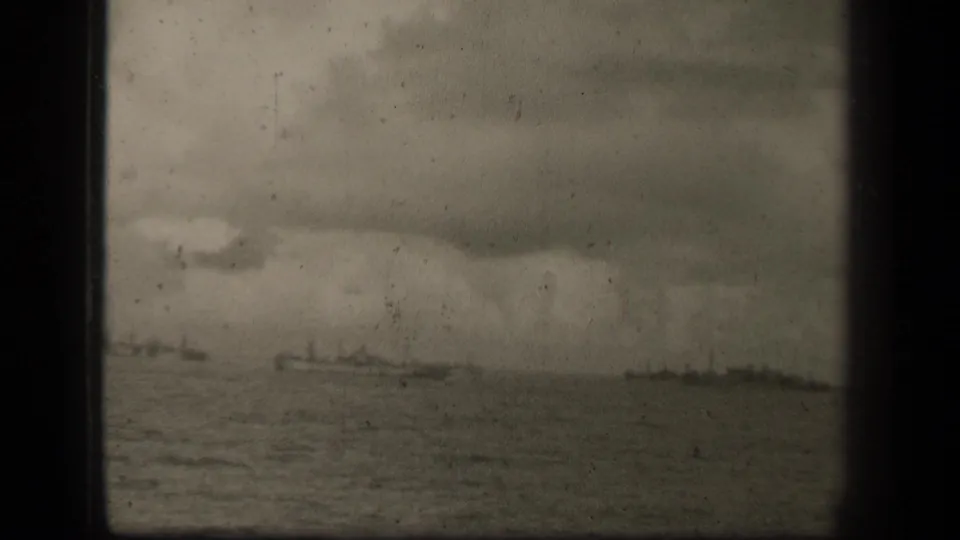 Distant warship silhouettes in Leyte Gulf, Philippines, based on metadata, seen across open water in a grainy 1944 8mm frame.