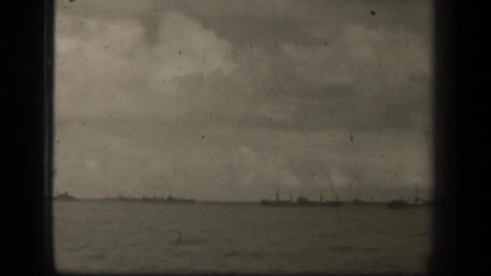 Soft 8mm footage shows open water in Leyte Gulf with small distant ships along the horizon beneath layered clouds.