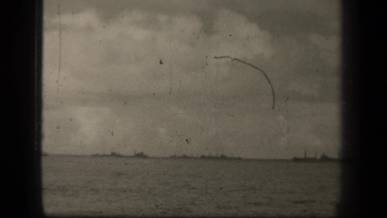 1944 Leyte Gulf footage showing a distant military ship on open water under an overcast sky, with visible 8mm gate edges and scratches.
