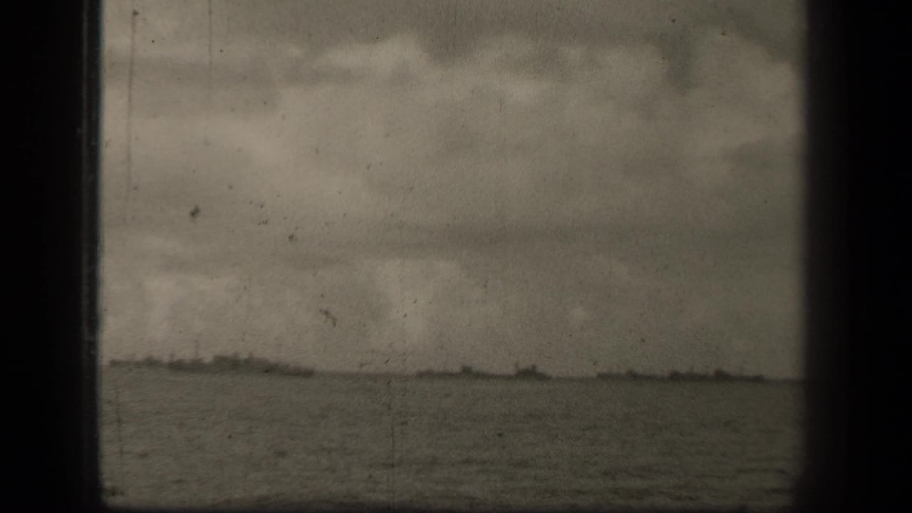 A wider 8mm view of Leyte Gulf water and horizon, with faint landforms or vessels barely visible beneath heavy cloud cover.