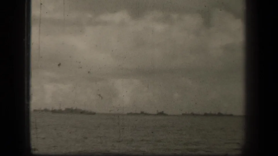 A wider 8mm view of Leyte Gulf water and horizon, with faint landforms or vessels barely visible beneath heavy cloud cover.