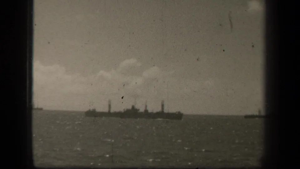 A large military ship appears in profile on Leyte Gulf waters, filmed at a distance on grainy 8mm stock in 1944.