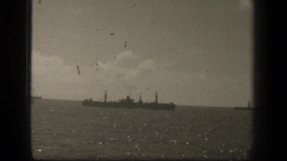 The ship remains visible on Leyte Gulf waters, with dark film borders, soft exposure, and a pale clouded sky in the background.