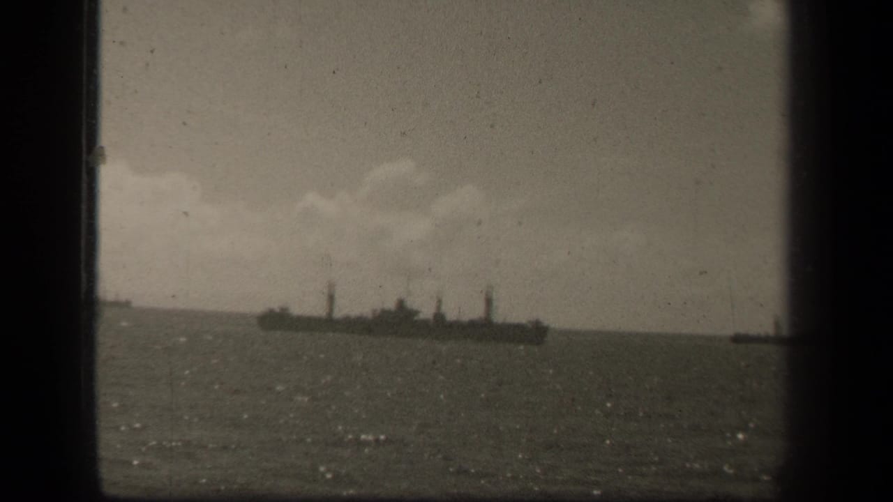 Distant ship on open water beneath a cloudy sky, framed by dark film edges.